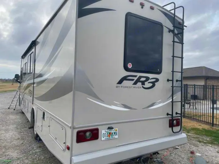 This FR3 by Forest River Class A RV rental is parked outdoors, showcasing its rear and side with a ladder and awnings.. Forest River Fr3 2015