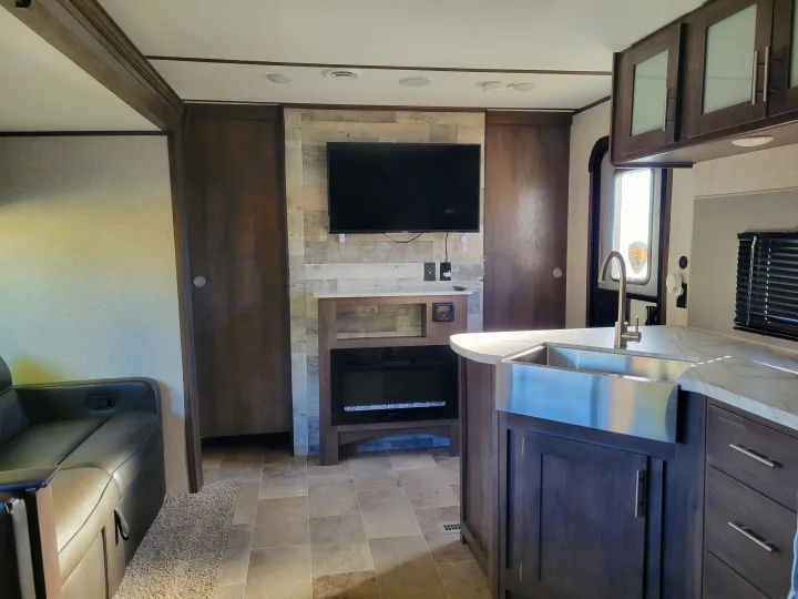 Luxurious RV rental interior: large screen TV, fireplace, and full kitchen with sink. Perfect for a comfortable road trip.. Coleman 263 BH Lantern Edition 2021