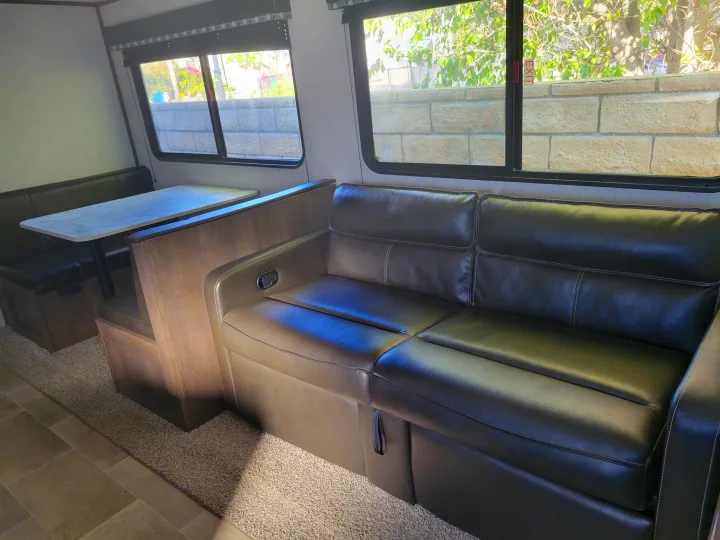 Experience comfort in this RV rental: spacious dinette, plush sofa, and bright windows define this travel trailer interior.. Coleman 263 BH Lantern Edition 2021