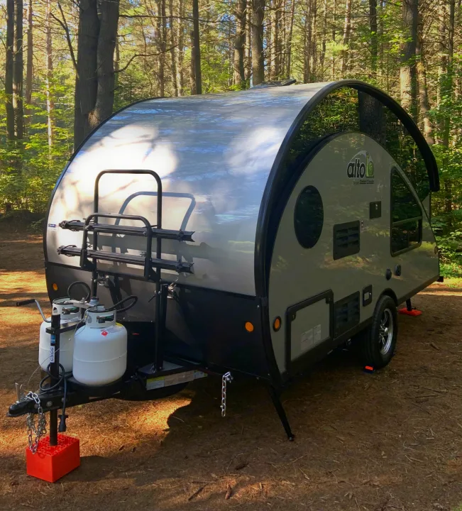 Compact Alto RV rental in a sunny forest. This modern travel trailer, with a bike rack and propane tanks, is ready for outdoor adventure.. Safari Condo Alto R1723 Bunkhouse 2022