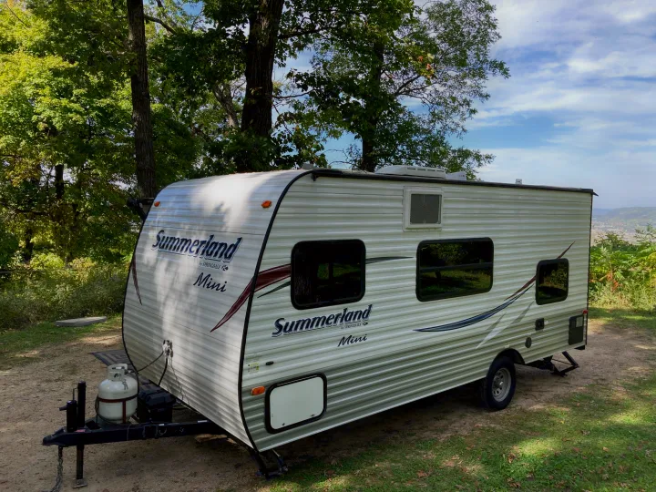 This rv rental, a Summerland Mini travel trailer, is set up at a scenic campsite overlooking a valley. Perfect for outdoor adventures.. Keystone RV Summerland Mini 2016