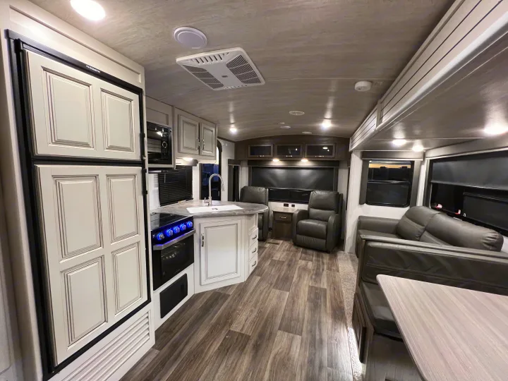 RV rental interior: A bright, modern kitchen with a Dometic fridge, oven, and sink, plus a comfy living area.. Keystone Cougar Half-Ton 2021
