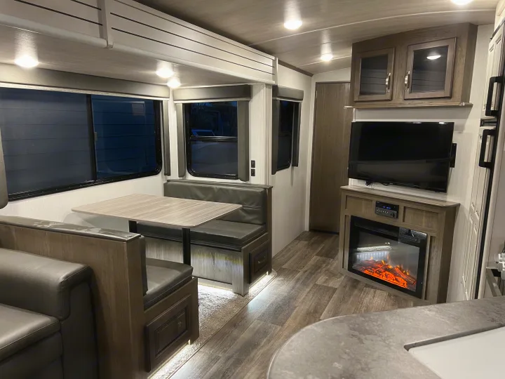 Modern RV rental interior showing a dinette, TV, and fireplace, designed for comfortable travel and compact living.. Keystone Cougar Half-Ton 2021