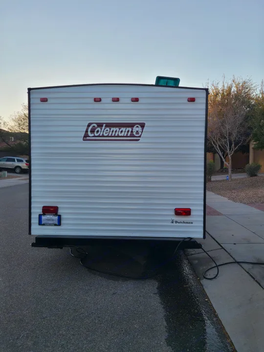 Rear of a white Coleman travel trailer, ideal for an RV rental. Parked on asphalt, showing taillights & temporary plate.. Coleman Latern 17b 2022