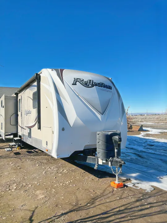 Experience freedom with this Grand Design Reflection travel trailer, an ideal rv rental, parked on a dirt lot with melting snow.. Grand Design Reflection 2015