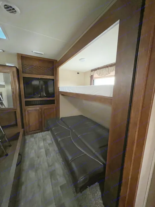 Cozy RV rental interior featuring a living area with TV, dark futon, and a bright bunk bed for comfortable travel.. Grand Design Reflection 2015