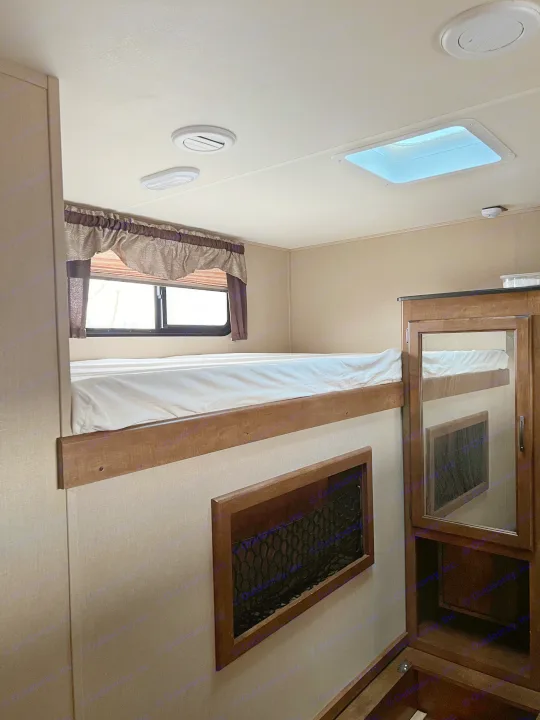 Inside an RV rental: a cozy bunk bed with window, ceiling lights, a skylight, and mirrored storage.. Grand Design Reflection 2015