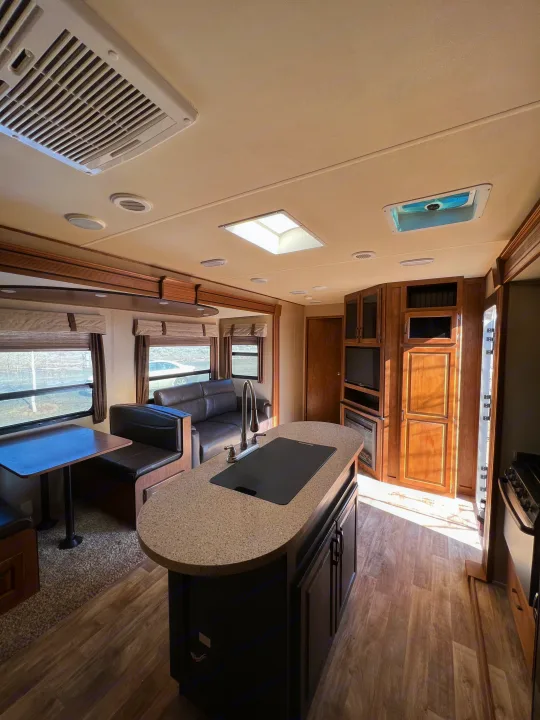 Bright, modern RV rental interior featuring a full kitchen island, dining booth, and comfortable living space.. Grand Design Reflection 2015