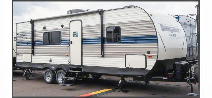 White and gray striped travel trailer, ideal for an rv rental, with blue accents, door, windows, and leveling jacks visible.. KZ Sportsmen SE 260BHSE 2020