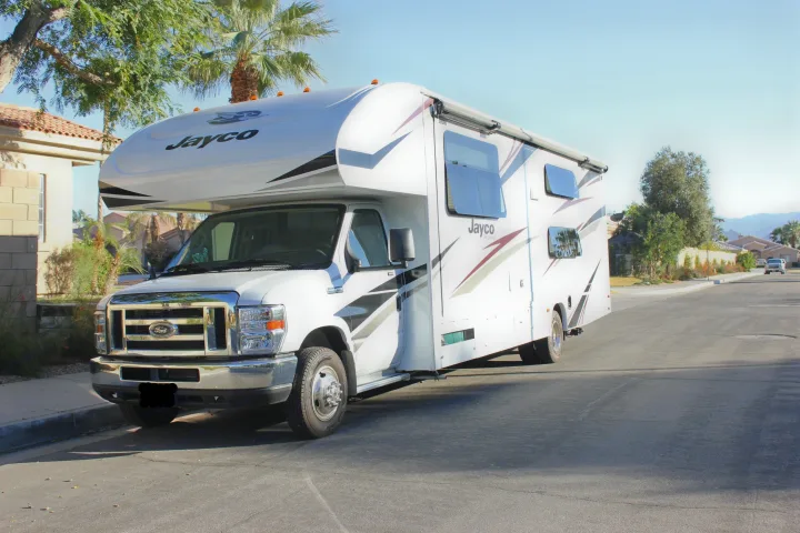 White Jayco RV rental parked on a sunny street, ready for adventure. This camper or motorhome is perfect for travel.. Jayco Redhawk 2020