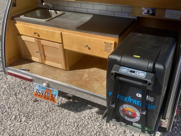 Rear galley of a Utah teardrop trailer RV rental with sink, cabinets, and pull-out fridge/freezer.. Little Guy Silver Shadow 2015