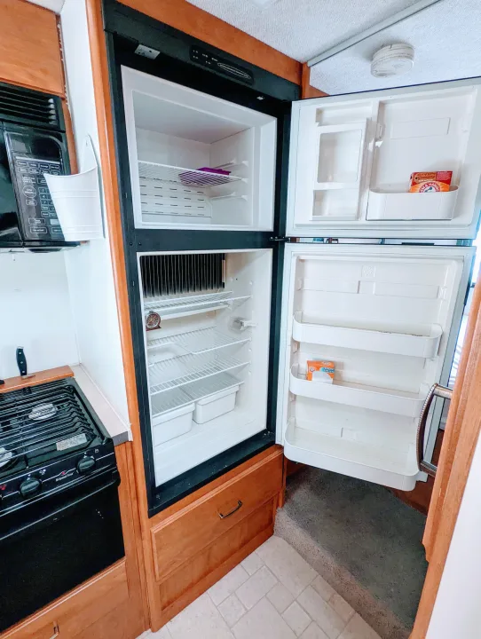 Inside an RV rental: a clean kitchen area featuring an open refrigerator, microwave, and stovetop.. Fleetwood Tioga 2005