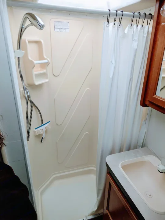 Your RV rental offers a compact beige shower, chrome faucet, small sink, and wood vanity for convenience.. Fleetwood Tioga 2005