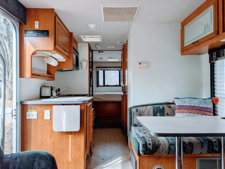 Cozy RV rental interior featuring a compact kitchen, dinette, and comfortable rear bedroom, ideal for travel adventures.. Fleetwood Tioga 2005