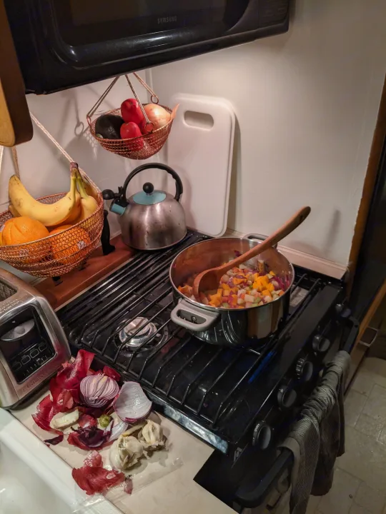 Cooking in a compact RV rental kitchen: chopped veggies on the stovetop, fruit baskets, and a microwave oven.. Fleetwood Tioga 2005