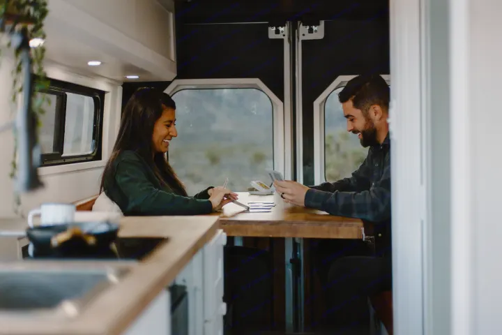 Smiling couple plays cards in their RV rental, enjoying a cozy adventure.. Dodge Sprinter 2019