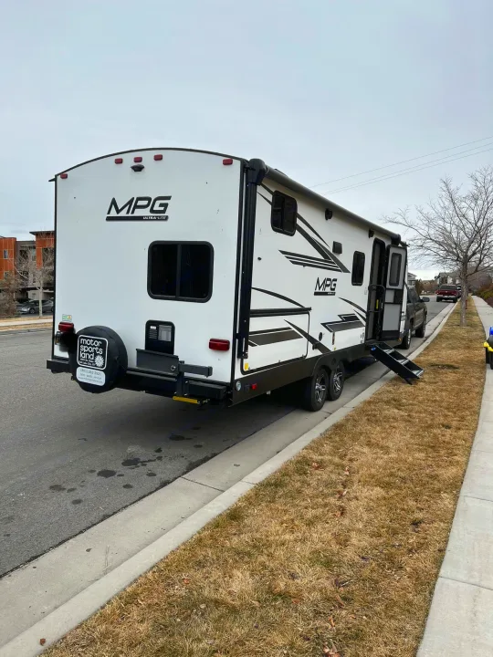White MPG Ultra-Lite RV rental parked on a residential street with its entry steps down.. Cruiser RV MPG Ultra Lite 2500BH 2021