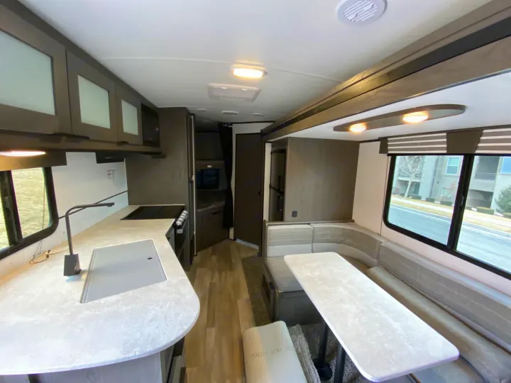Bright RV rental interior featuring a full kitchen with counter/sink and a comfortable dinette with U-shaped booth seating.. Cruiser RV MPG Ultra Lite 2500BH 2021