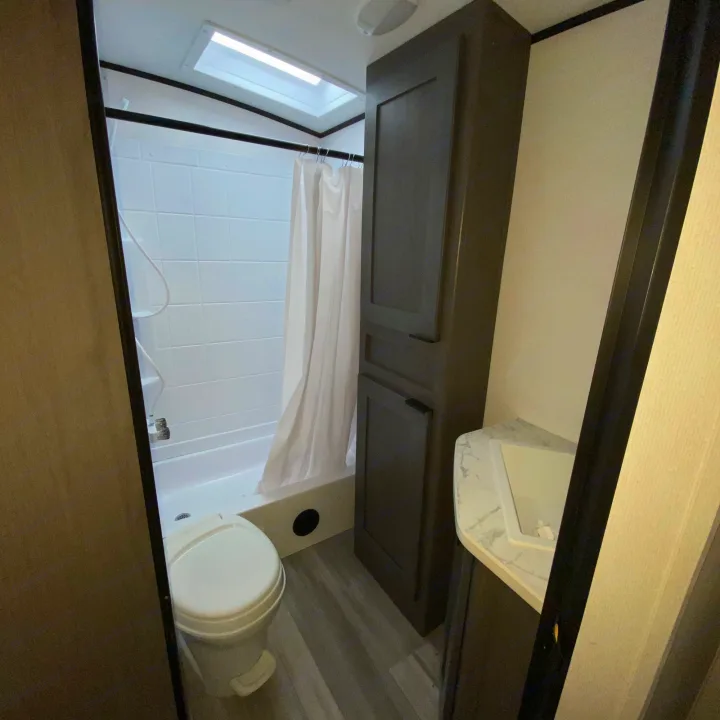 Clean RV rental bathroom featuring a toilet, shower with curtain, vanity, and storage cabinets.. Cruiser RV MPG Ultra Lite 2500BH 2021