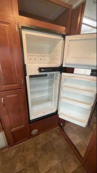 This clean, empty RV rental refrigerator and freezer, built into warm wood cabinetry, is ready for your food supplies.. Winnebago Minnie Winnie 2014
