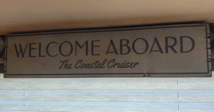 A charming "Welcome Aboard The Coastal Cruiser" sign inside an RV rental, setting a maritime mood.. Jayco Redhawk 2020