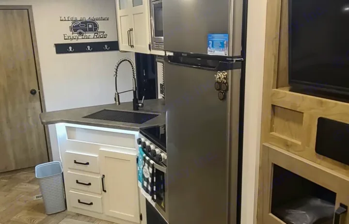 Modern RV rental interior: compact kitchen with stainless steel appliances & adventure decor.. Palomino Puma 28DBFQ 2021