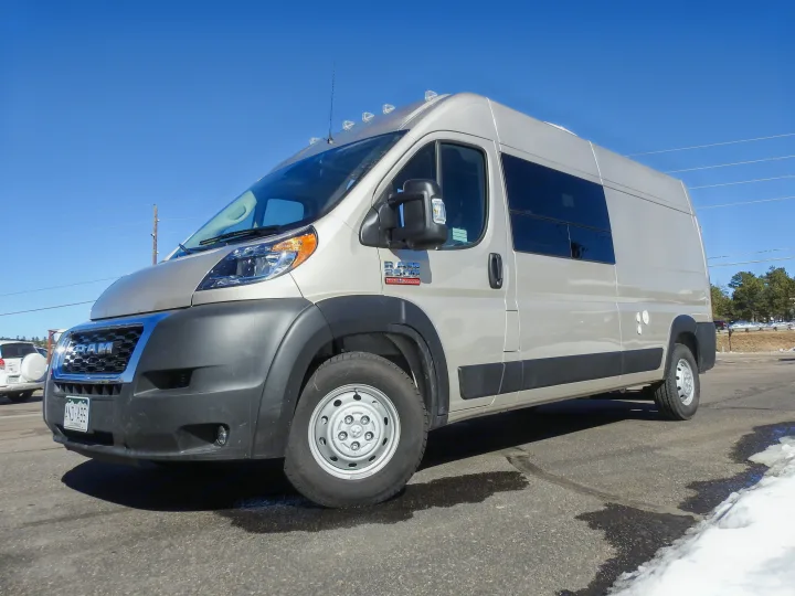 Light tan Ram ProMaster RV rental van parked on asphalt under a blue sky, ready for travel adventures.. Dodge Promaster- Summit X Edition OA9 2021