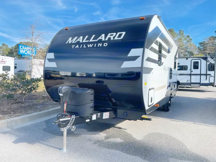 A modern black and white Mallard Tailwind travel trailer, ideal for an RV rental. Parked outside a dealership.. Heartland Mallard 180BH 2022