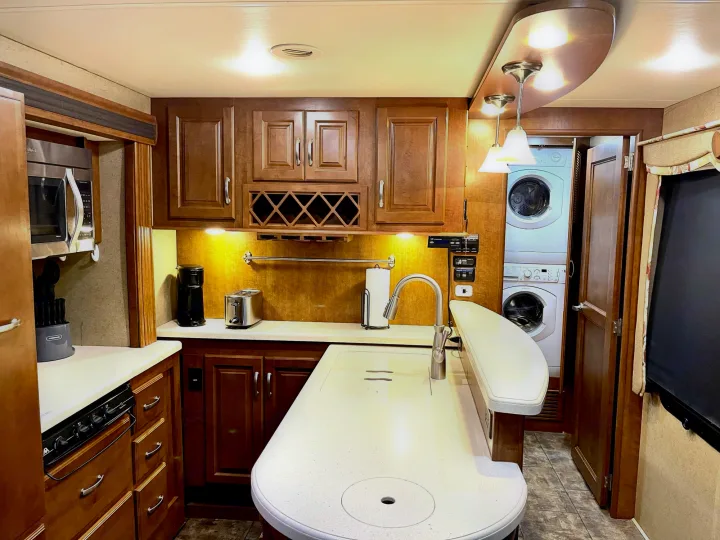 Spacious RV rental kitchen with modern appliances, sink, and washer/dryer for comfortable mobile living.. Thor Challenger 2015