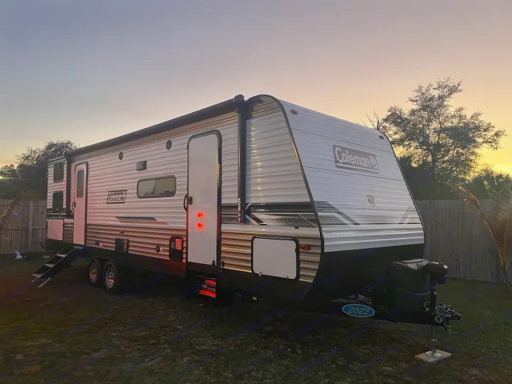 Modern Coleman RV rental parked at dusk. Brightly lit exterior for travel and camping adventures. A perfect leisure escape.. Dutchmen Coleman 2022