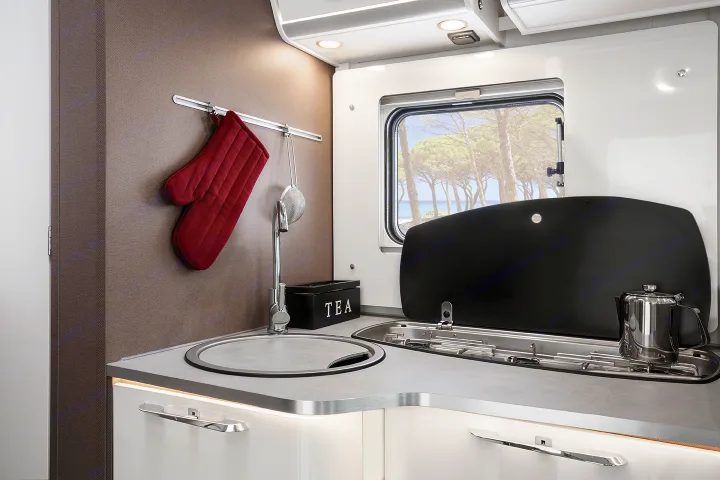 Well-equipped RV rental kitchen with sink, covered stove, and window view. Ideal for mobile living.. Etrusco Etrusco T7400SBC 2021
