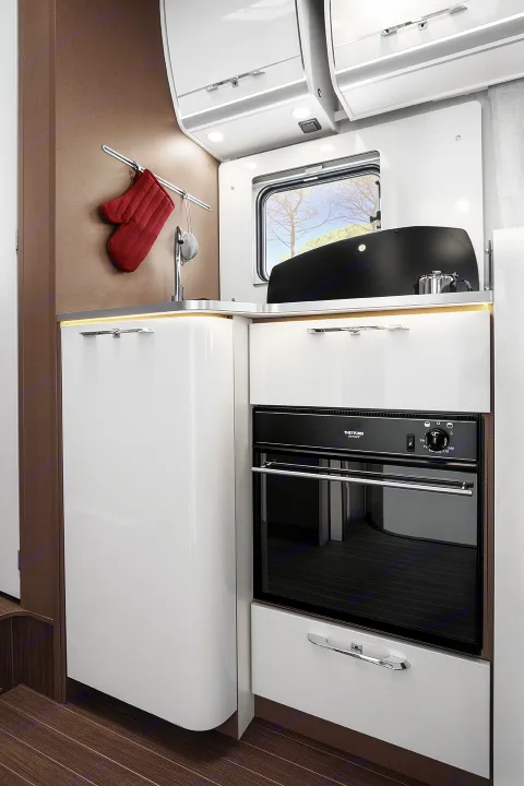 Modern RV rental kitchenette with oven, sink, and glossy white cabinets. Perfect for road trip cooking.. Etrusco Etrusco T7400SBC 2021