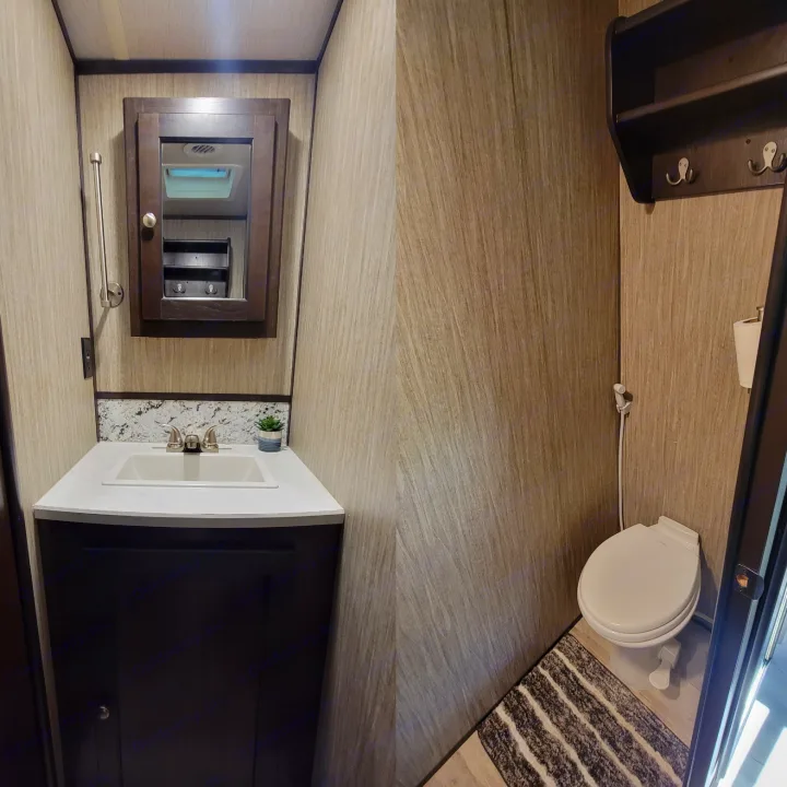 Efficient RV rental bathroom: vanity with sink, mirrored cabinet, toilet with bidet, & storage shelf.. Heartland RVs Sundance 2018