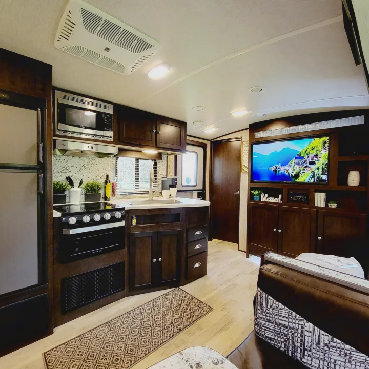 Spacious RV rental interior with a modern kitchen, inviting living area, and TV. Ideal for comfortable travel.. Heartland RVs Sundance 2018