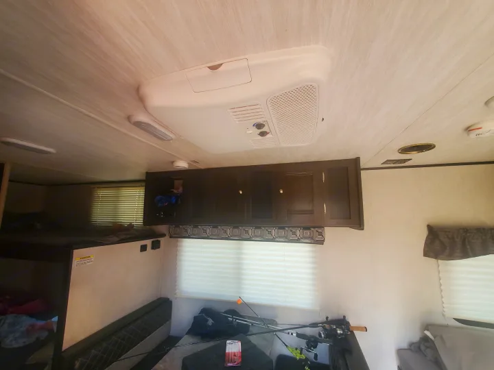 RV rental interior with ceiling-mounted AC, bunk beds, storage cabinets, and fishing gear, ideal for camping adventures.. Heartland RVs Pioneer 2020
