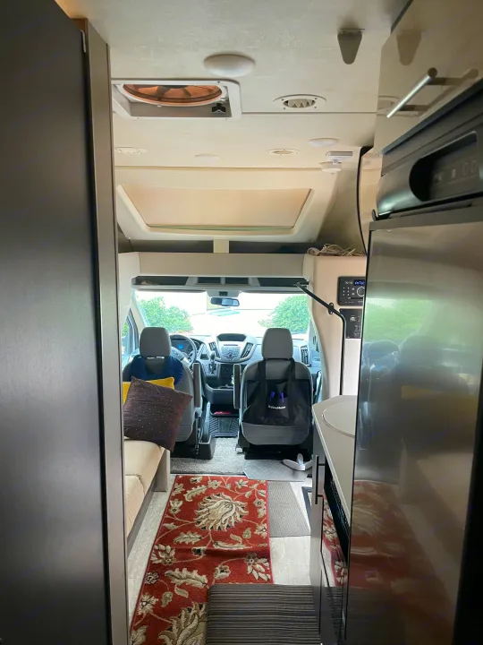 RV rental interior: view to front cabin with driver's area, comfy seating, kitchen appliance & patterned rug. Ready for travel!. Thor Compass 2016