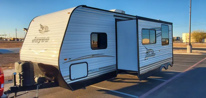 Brightly lit Jayco travel trailer with a slide-out, perfect for your next rv rental adventure. Parked outdoors under a clear sky.. Jayco Jay Flight 2017