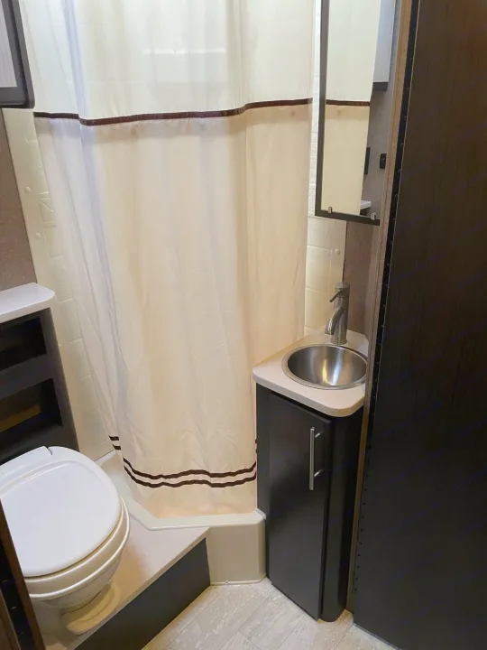 Inside your RV rental: a compact bathroom with a shower, toilet, sink, and mirrored vanity, designed for convenience.. Thor Compass 2016