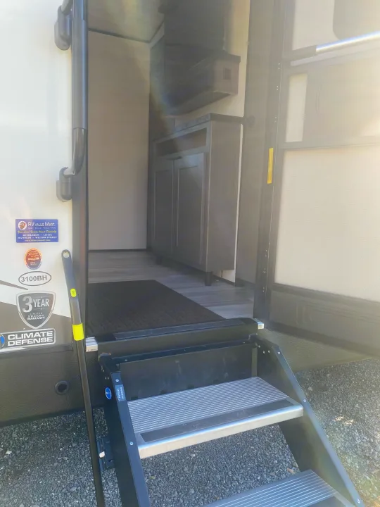 Open door of an RV rental, showing its interior, sturdy steps, and grab bar. Ready for your next adventure!. Cruiser RV MPG Ultra Lite 2021