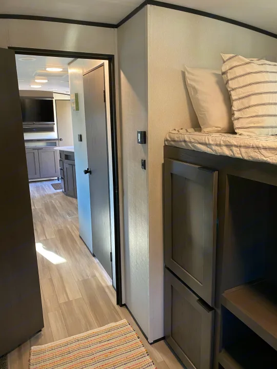 Step into this inviting RV rental. Features bunk beds, light flooring, and a view of the modern kitchen/living area.. Cruiser RV MPG Ultra Lite 2021