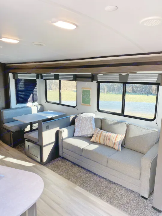 Inviting RV rental interior showcasing a dinette, comfy sofa with pillows, and expansive windows offering scenic views.. Cruiser RV MPG Ultra Lite 2021