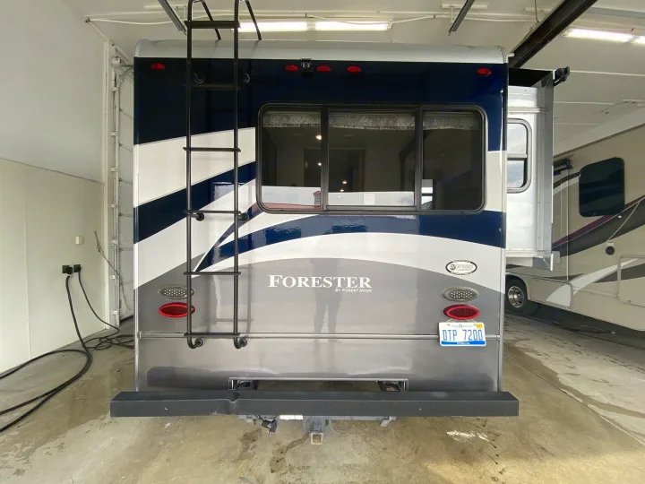 Explore this RV rental: a blue and silver Forester motorhome from the rear, showing its ladder, window, and license plate.. Forester Forester Motorhome 2017