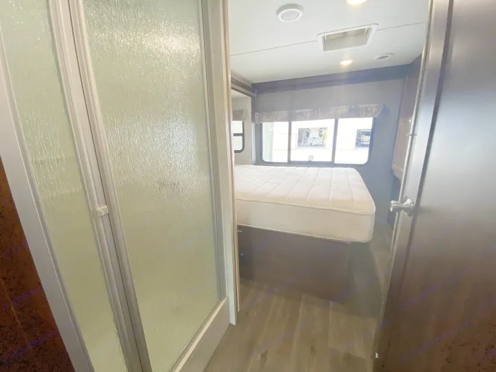 This RV rental's bedroom interior features a white mattress, window with outdoor view, and a frosted glass shower on the left.. Forester Forester Motorhome 2017