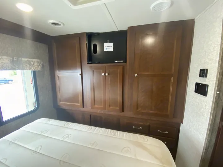 Spacious RV rental bedroom with Serta mattress, built-in wooden cabinets, and TV mount, offering comfortable travel.. Forester Forester Motorhome 2017