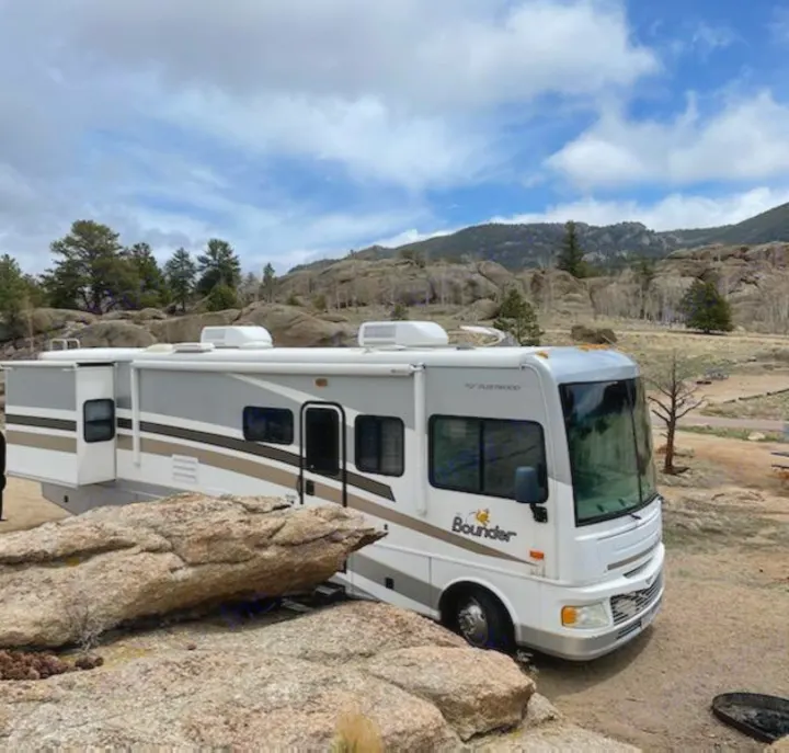 An RV rental is parked among large rocks in a picturesque mountain camping site, ready for adventure.. Fleetwood Other 2006