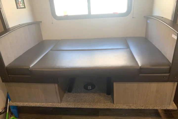RV rental interior: A dinette with gray cushions, light wood-look base, and window above, converts to a bed.. Keystone RV Hideout 2021