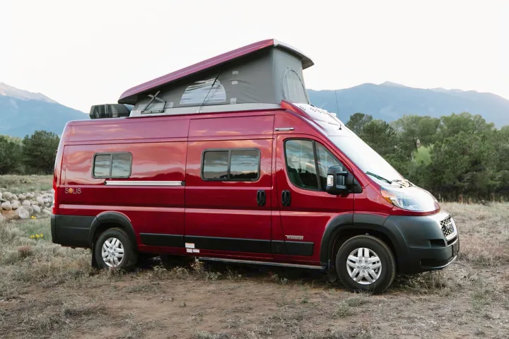 Red Winnebago Solis pop-top RV rental parked in a scenic mountain landscape, ready for adventure.. Winnebago Solis 2021