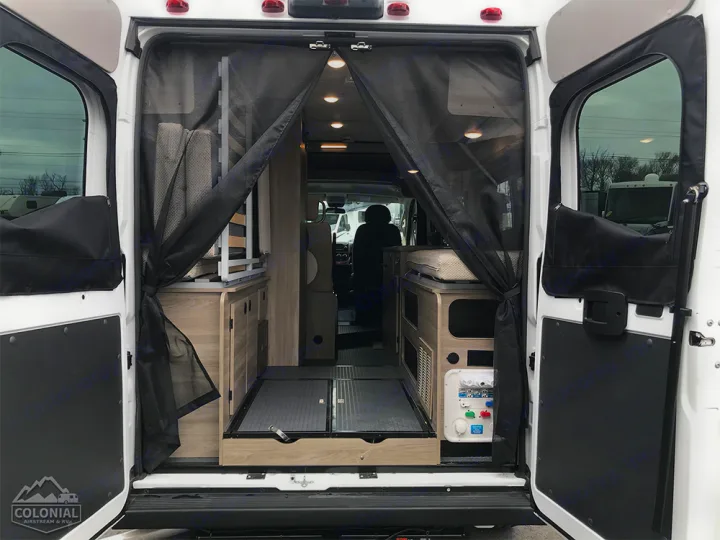 RV rental: Through open rear doors, a camper van's interior is seen with a mesh screen, compact cabinetry, and pull-out bed base.. Winnebago Solis 2021