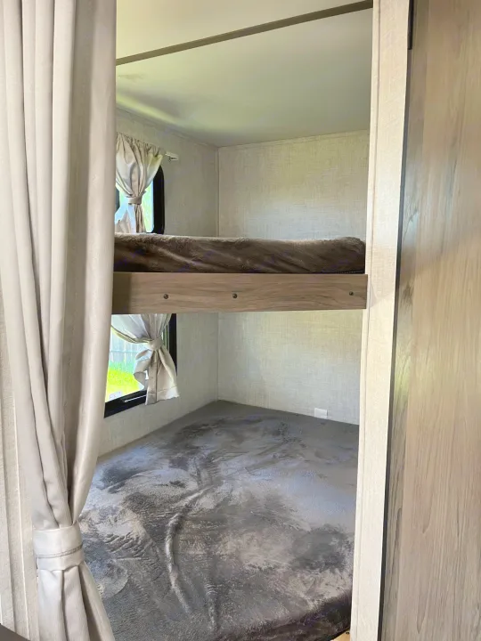 Inside an rv rental: dual bunk beds with curtains & windows offer compact sleeping. Ideal for travel accommodation.. Travel Lite Superlite 2022