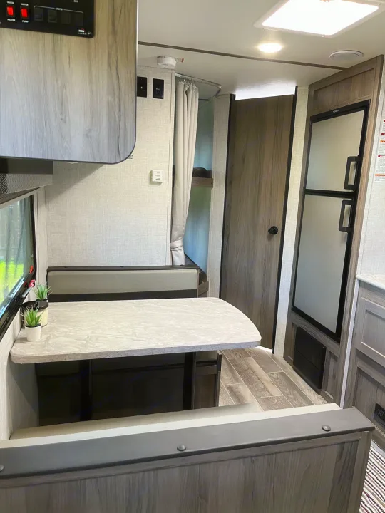 Modern RV rental interior with dinette, refrigerator, and bunk beds. Perfect for comfortable journeys and family. Travel Lite Superlite 2022
